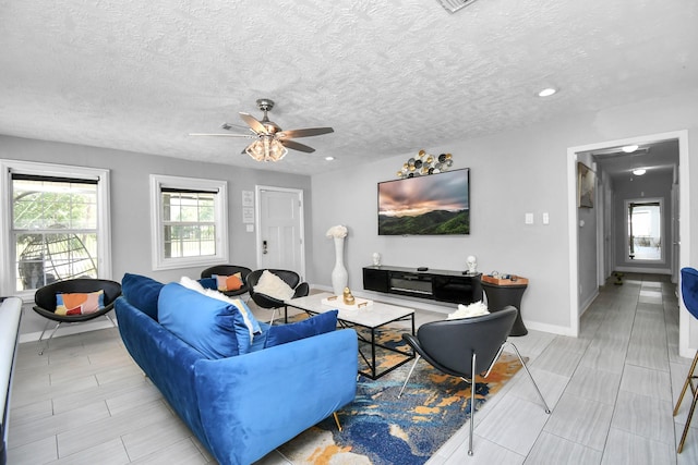 living room featuring ceiling fan and a textured ceiling