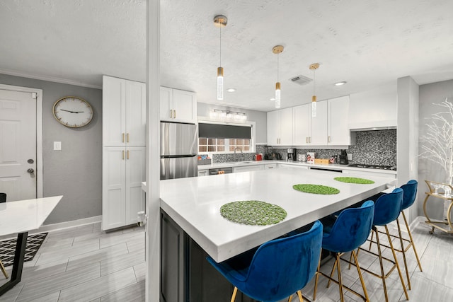 kitchen featuring backsplash, sink, hanging light fixtures, white cabinetry, and stainless steel appliances