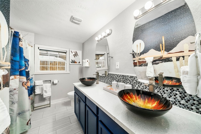 bathroom featuring vanity, a shower with curtain, toilet, a textured ceiling, and tasteful backsplash