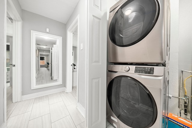 washroom featuring stacked washer and dryer and light tile patterned flooring