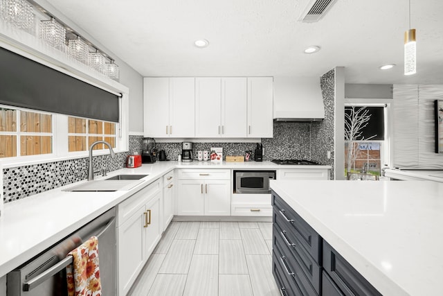 kitchen with sink, appliances with stainless steel finishes, pendant lighting, white cabinets, and custom exhaust hood