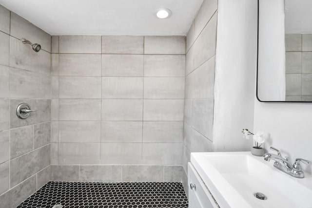 bathroom with a tile shower and vanity