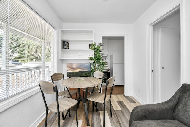 dining space with light hardwood / wood-style flooring and built in features