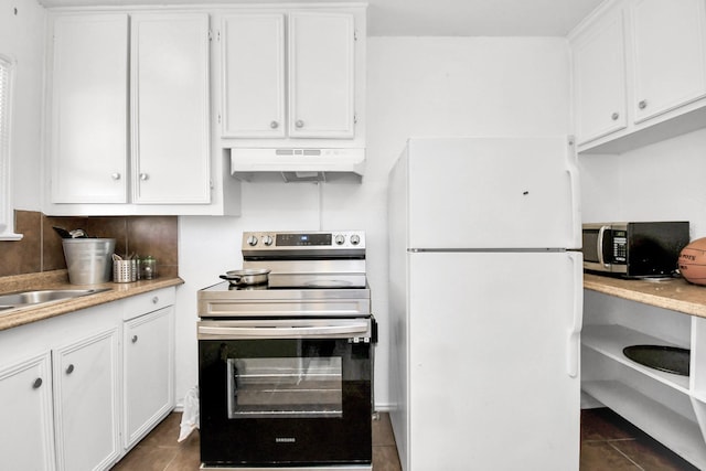 kitchen with dark tile patterned flooring, white cabinets, stainless steel appliances, and extractor fan