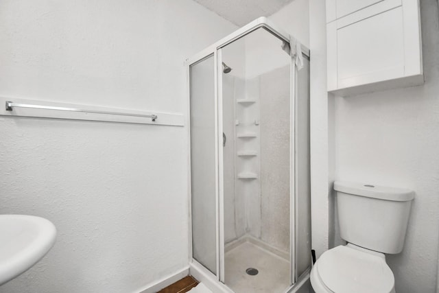 bathroom with a shower with shower door and toilet