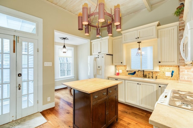 kitchen with sink, white appliances, hanging light fixtures, a center island, and tasteful backsplash