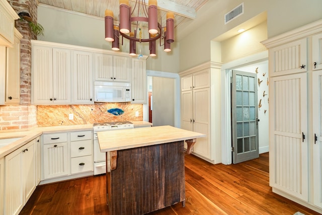 kitchen with backsplash, dark hardwood / wood-style flooring, a chandelier, white appliances, and beam ceiling