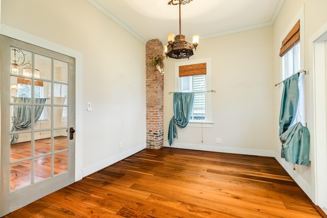 spare room with wood-type flooring, ornamental molding, a healthy amount of sunlight, and baseboard heating