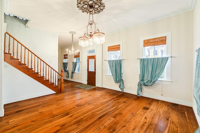 entrance foyer featuring hardwood / wood-style floors, crown molding, and a chandelier