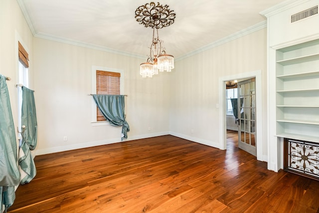 unfurnished room with crown molding, dark hardwood / wood-style flooring, built in shelves, and a notable chandelier