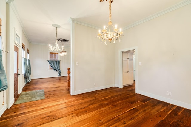 spare room featuring an inviting chandelier, ornamental molding, and hardwood / wood-style floors