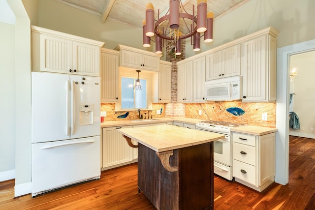 kitchen with pendant lighting, white appliances, a center island, and an inviting chandelier