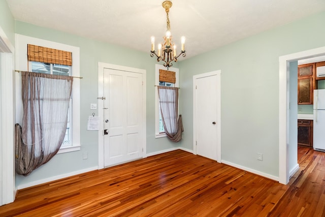 foyer entrance with hardwood / wood-style flooring, plenty of natural light, and a chandelier