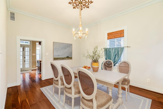 dining room with dark wood-type flooring, crown molding, and a chandelier