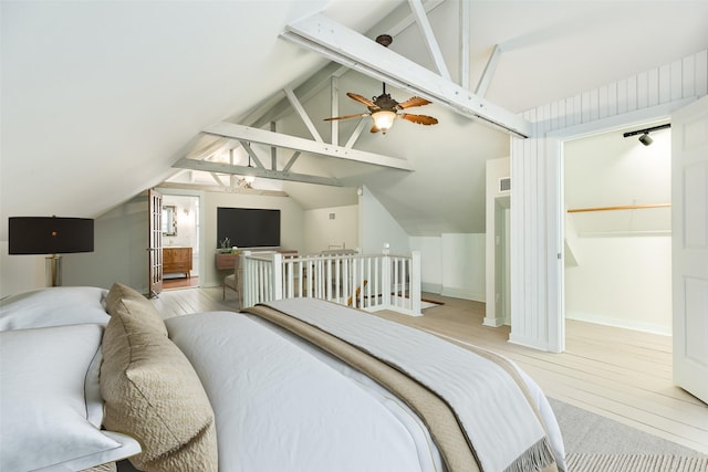 bedroom featuring a spacious closet, lofted ceiling with beams, and light wood-type flooring