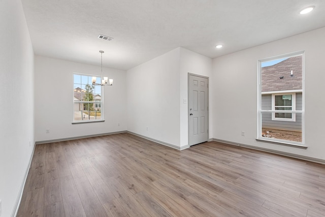 empty room featuring light hardwood / wood-style flooring and a chandelier