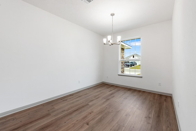 spare room with wood-type flooring and a chandelier