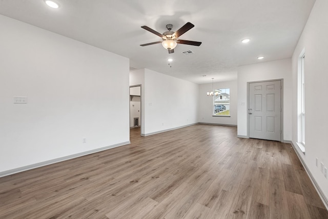 unfurnished living room featuring light hardwood / wood-style floors and ceiling fan with notable chandelier