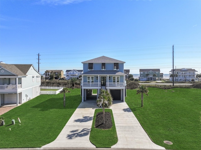 coastal inspired home featuring a carport, roof with shingles, concrete driveway, and a front yard