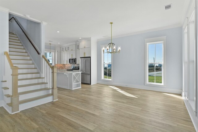 unfurnished living room featuring crown molding, a chandelier, and light wood-type flooring