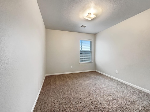 empty room with carpet floors and a textured ceiling