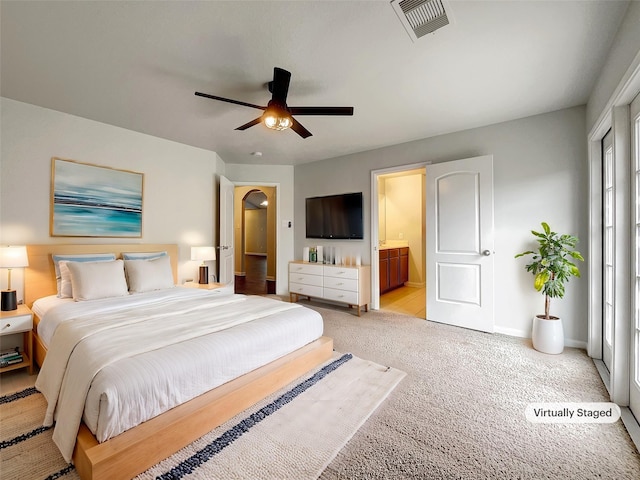 bedroom with multiple windows, ensuite bathroom, ceiling fan, and light colored carpet