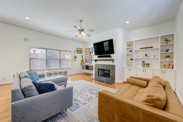 living room featuring a fireplace, light wood-type flooring, and ceiling fan