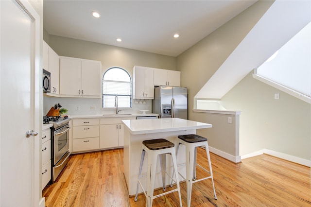 kitchen with a center island, stainless steel appliances, light wood-type flooring, white cabinetry, and sink