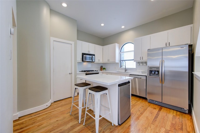 kitchen with a kitchen island, white cabinets, appliances with stainless steel finishes, and a kitchen breakfast bar