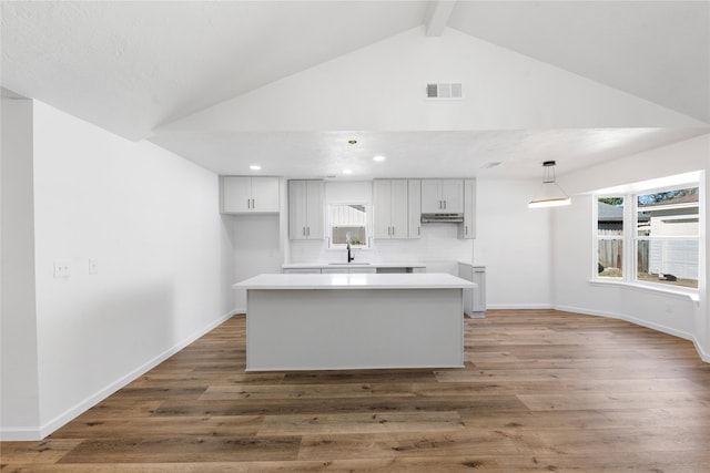 kitchen featuring pendant lighting, backsplash, lofted ceiling with beams, sink, and dark hardwood / wood-style floors