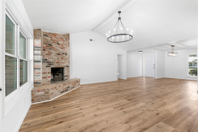 unfurnished living room featuring a notable chandelier, vaulted ceiling with beams, light hardwood / wood-style floors, and a brick fireplace