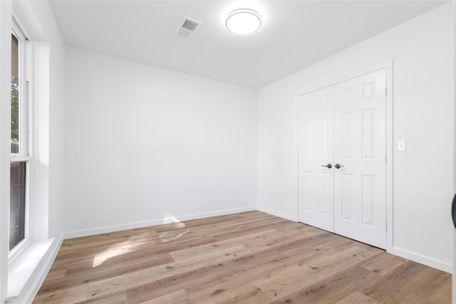 unfurnished bedroom with light wood-type flooring and a closet