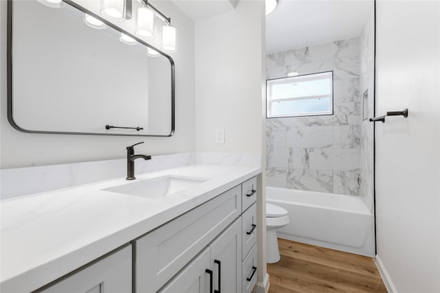 full bathroom featuring hardwood / wood-style flooring, vanity, toilet, and tiled shower / bath combo