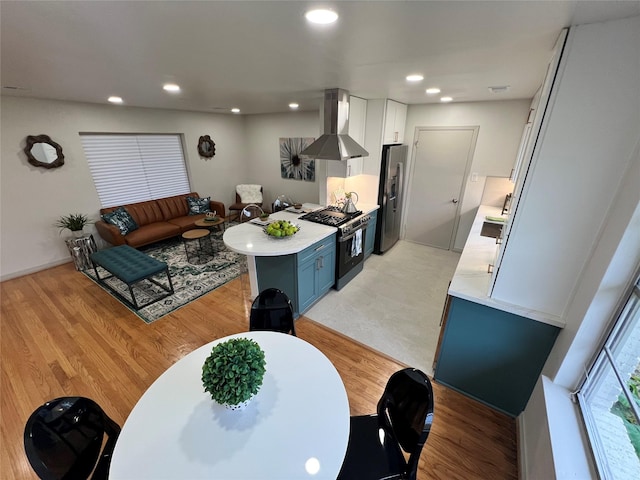 kitchen featuring stainless steel appliances, blue cabinets, light hardwood / wood-style floors, white cabinets, and exhaust hood