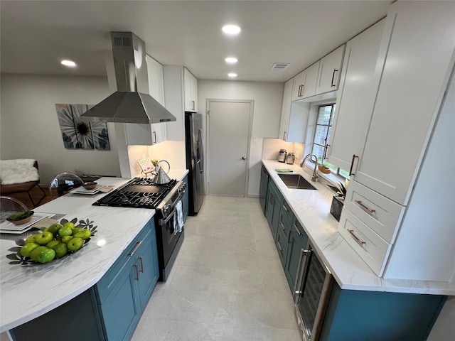 kitchen with blue cabinetry, sink, island range hood, white cabinets, and appliances with stainless steel finishes