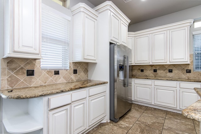 kitchen featuring stainless steel fridge, white cabinetry, and stone counters