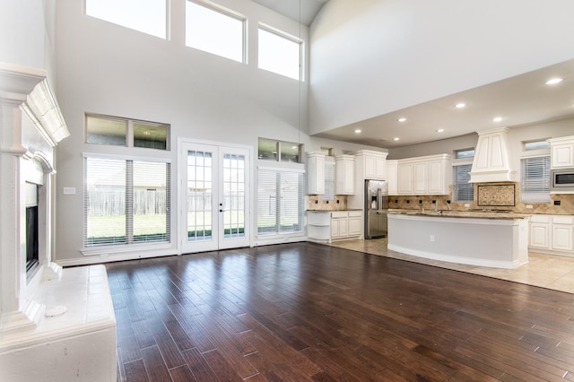 unfurnished living room with a high ceiling, light hardwood / wood-style floors, and french doors