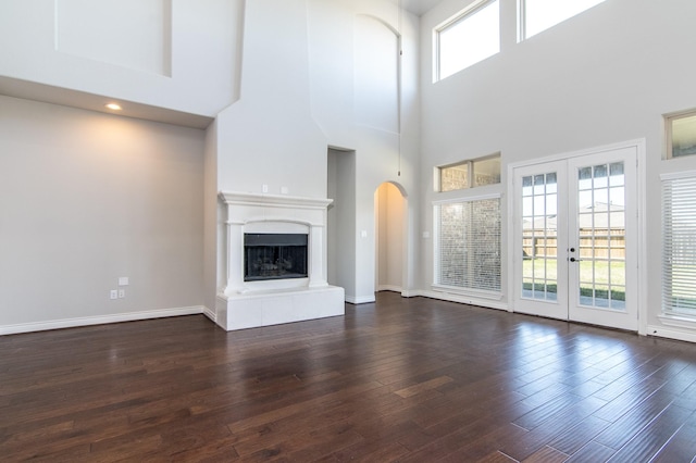 unfurnished living room with a high ceiling, dark hardwood / wood-style flooring, and french doors