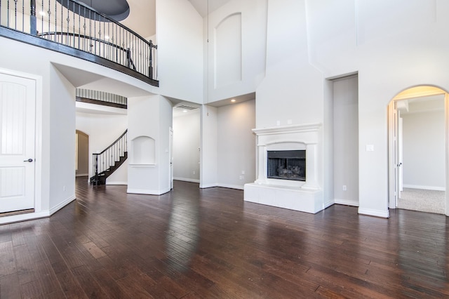 unfurnished living room with dark wood-type flooring and a high ceiling