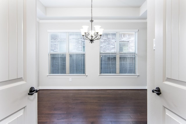 empty room with ornamental molding, dark hardwood / wood-style floors, and a notable chandelier