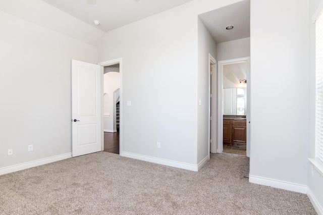 unfurnished bedroom featuring light carpet and ensuite bath