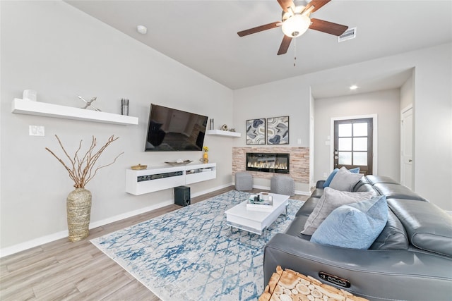 living room with a fireplace, ceiling fan, and light hardwood / wood-style flooring