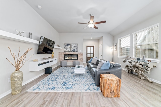 living room featuring a stone fireplace, ceiling fan, and light hardwood / wood-style floors