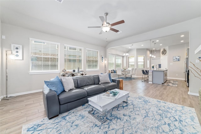 living room featuring ceiling fan with notable chandelier and light wood-type flooring