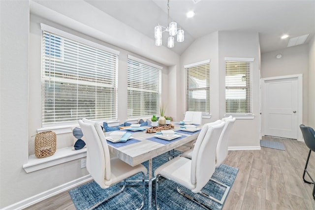 dining space with a chandelier, a healthy amount of sunlight, light hardwood / wood-style floors, and lofted ceiling