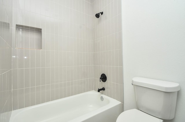 bathroom featuring tiled shower / bath combo and toilet