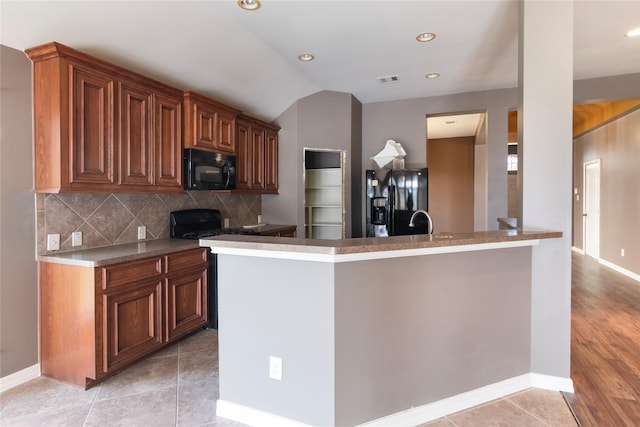 kitchen featuring tasteful backsplash, light tile patterned floors, black appliances, and vaulted ceiling