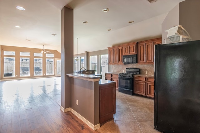 kitchen featuring ceiling fan, tasteful backsplash, pendant lighting, black appliances, and light wood-type flooring