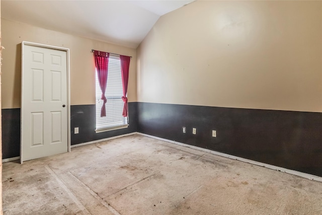 carpeted spare room featuring lofted ceiling