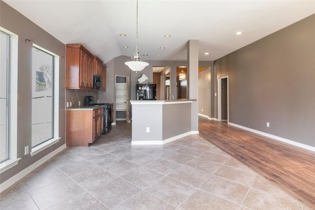 kitchen with backsplash, a healthy amount of sunlight, black appliances, hanging light fixtures, and lofted ceiling